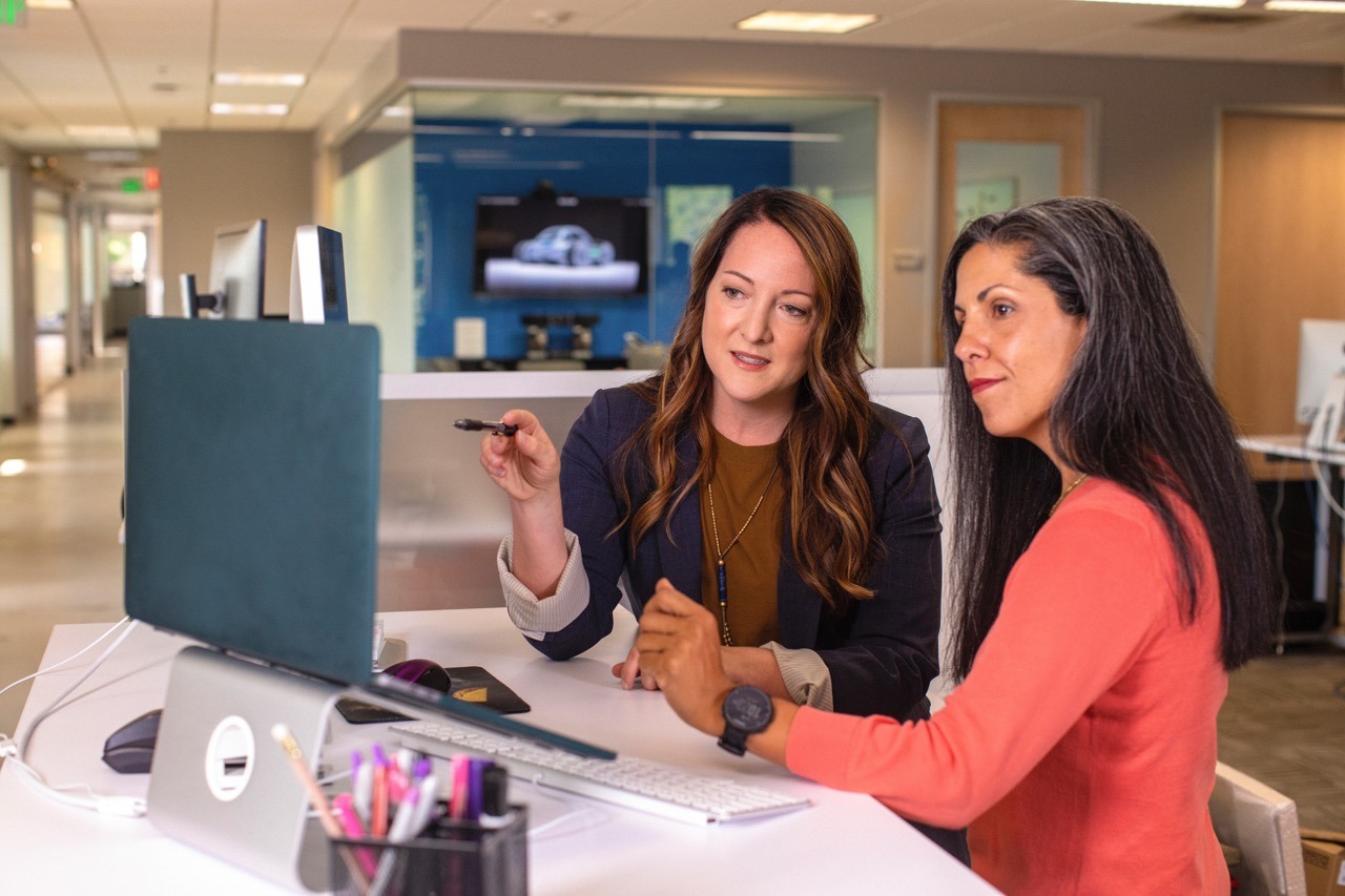 two women having a discussion while looking at a laptop
